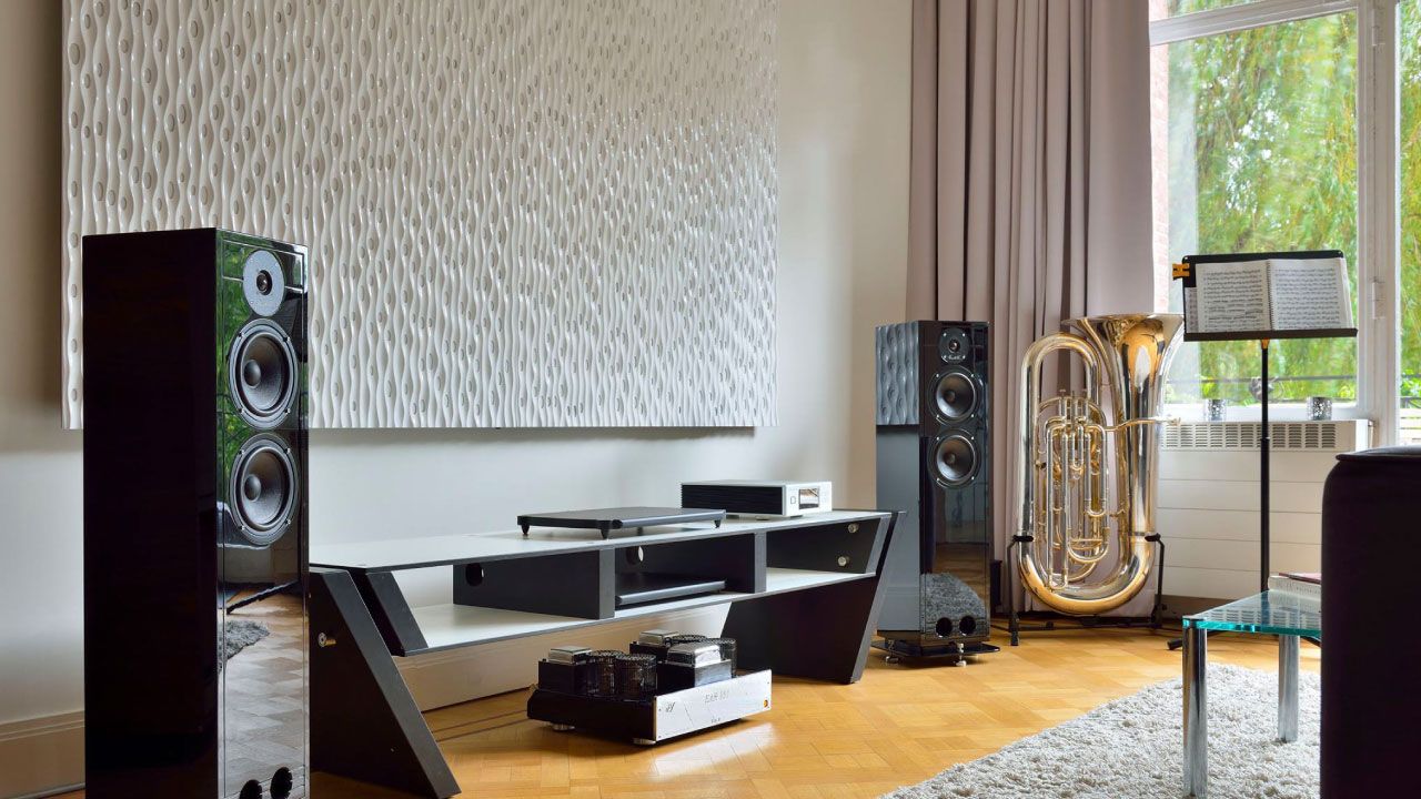 Wohnzimmer mit zwei schwarzen Lautsprechern, einem modernen schwarzen TV-Ständer und einer großen Tuba neben einem Fenster