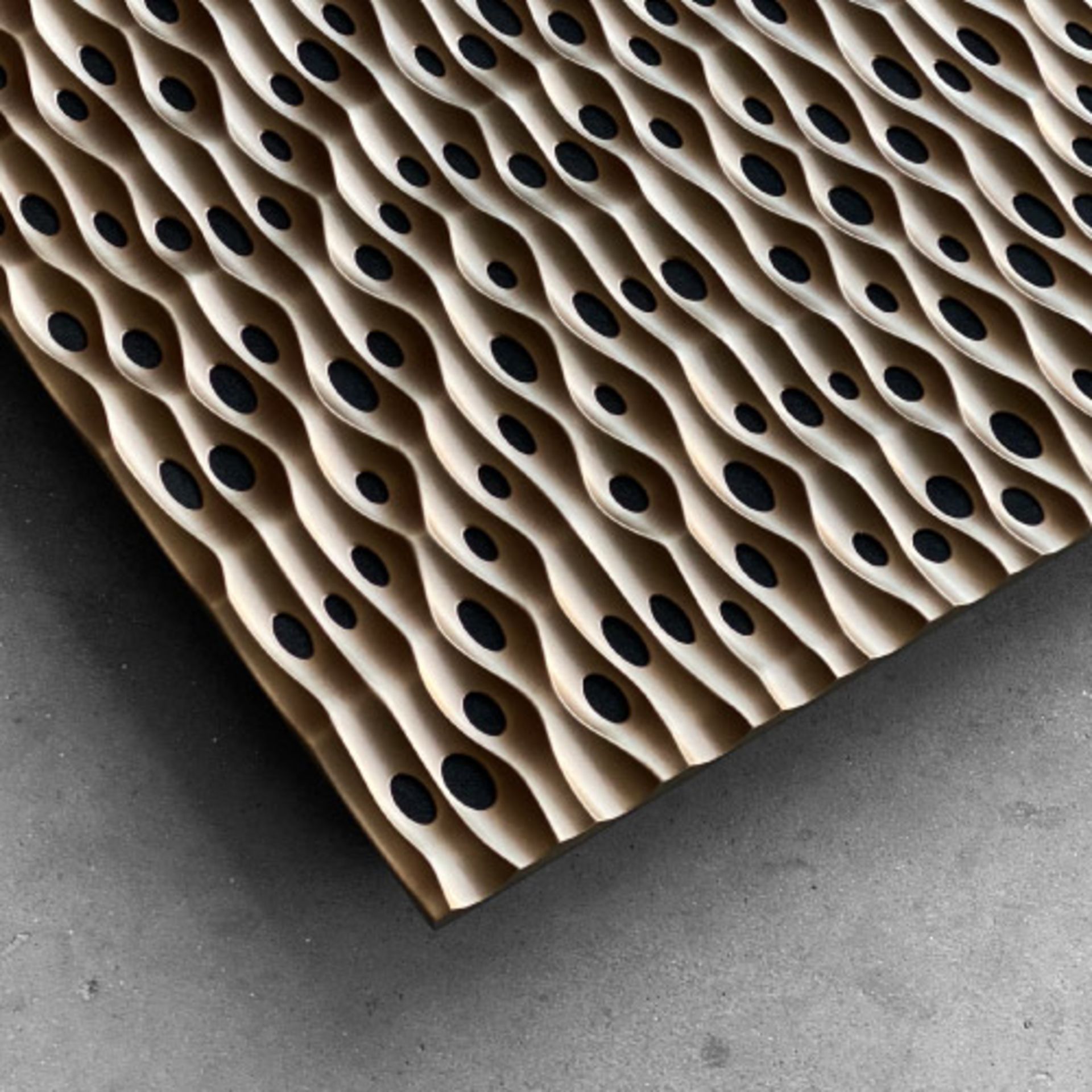 ArtNovion Sahara W Absorber mit wellenförmigem Muster und schwarzen ovalen Öffnungen, akustisches Paneel auf grauem Boden