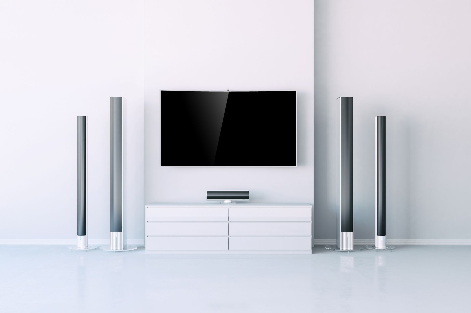 Flacher Fernseher an weißer Wand mit vier schlanken Lautsprechern und weißem Sideboard