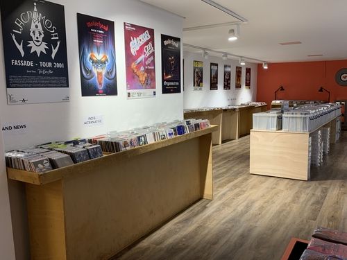 Innenansicht eines Musikladens mit Regalen voller CDs und Postern von Bands wie Lacrimosa und Motörhead an der Wand